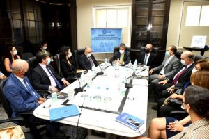 Foto mostra momento da reunião, com as pessoas participantes sentadas em uma sala, em volta de uma mesa.